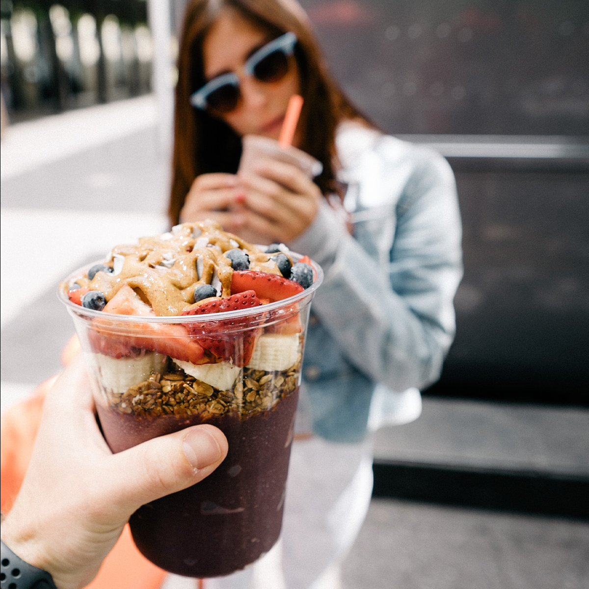 A hand holding up a drink topped with fruit