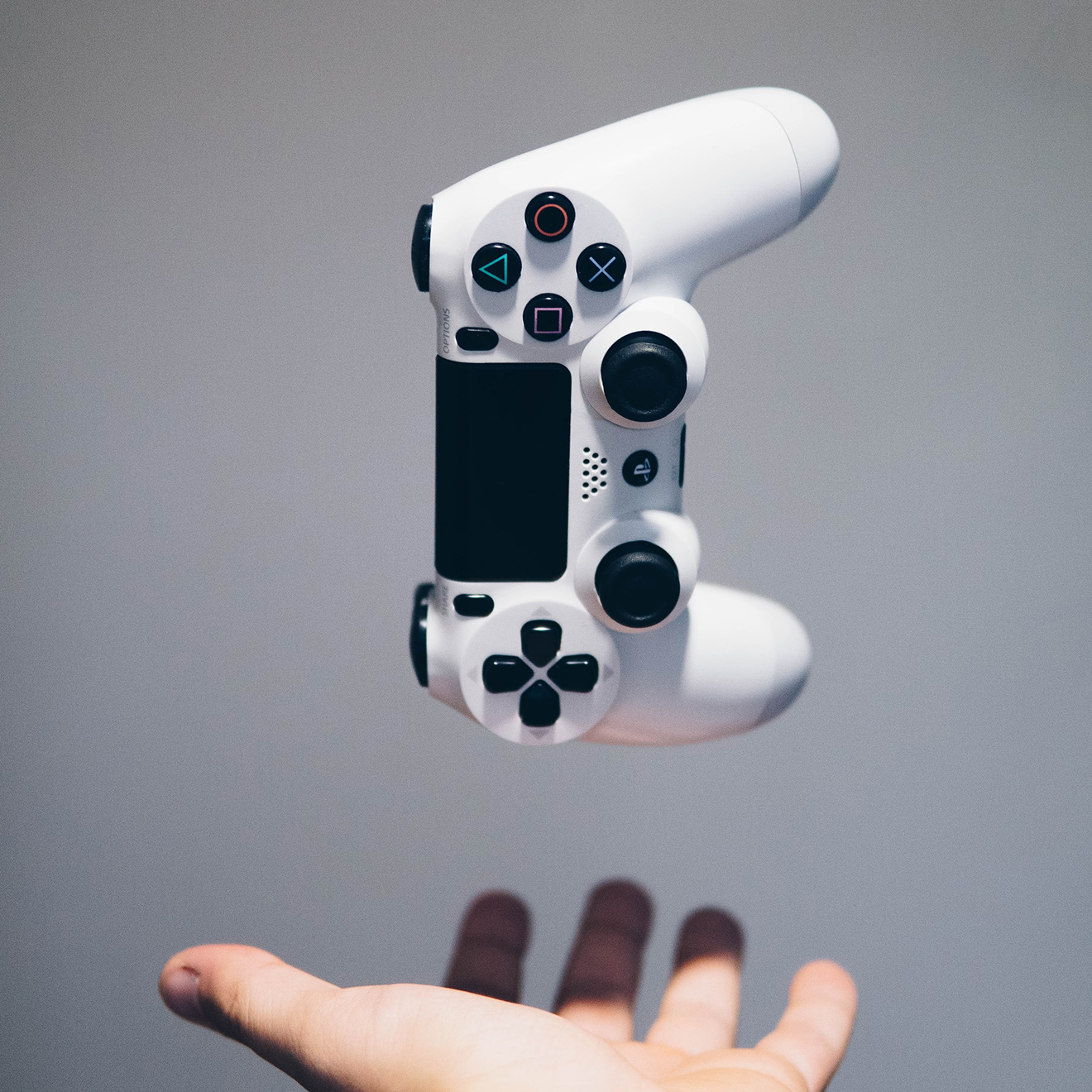 A PlayStation controller hovering above an outstretched hand